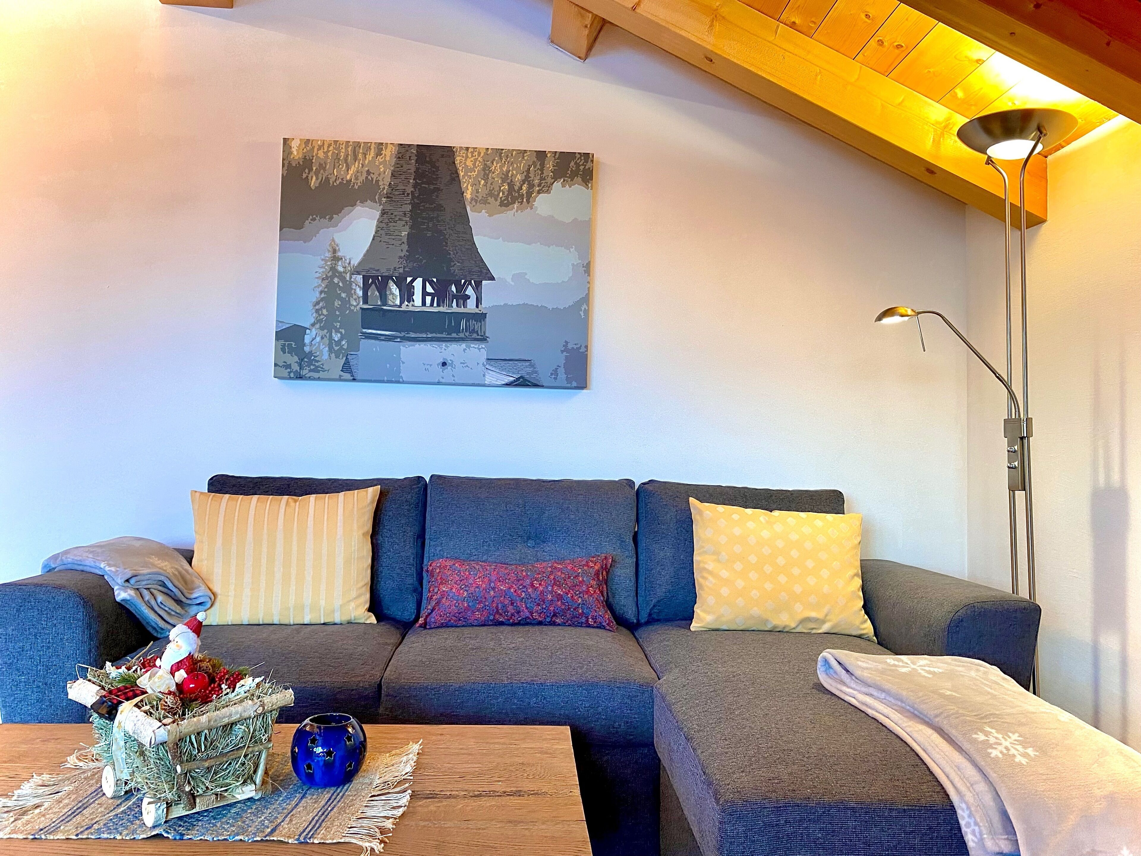A cozy living room with a sofa, a coffee table with a nativity scene, and a painting of a tree on the wall.