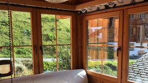 A wooden cabin with a bed, large windows, and a hanging light fixture.