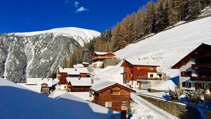A snow-covered mountain village with wooden cabins and a clear blue sky.