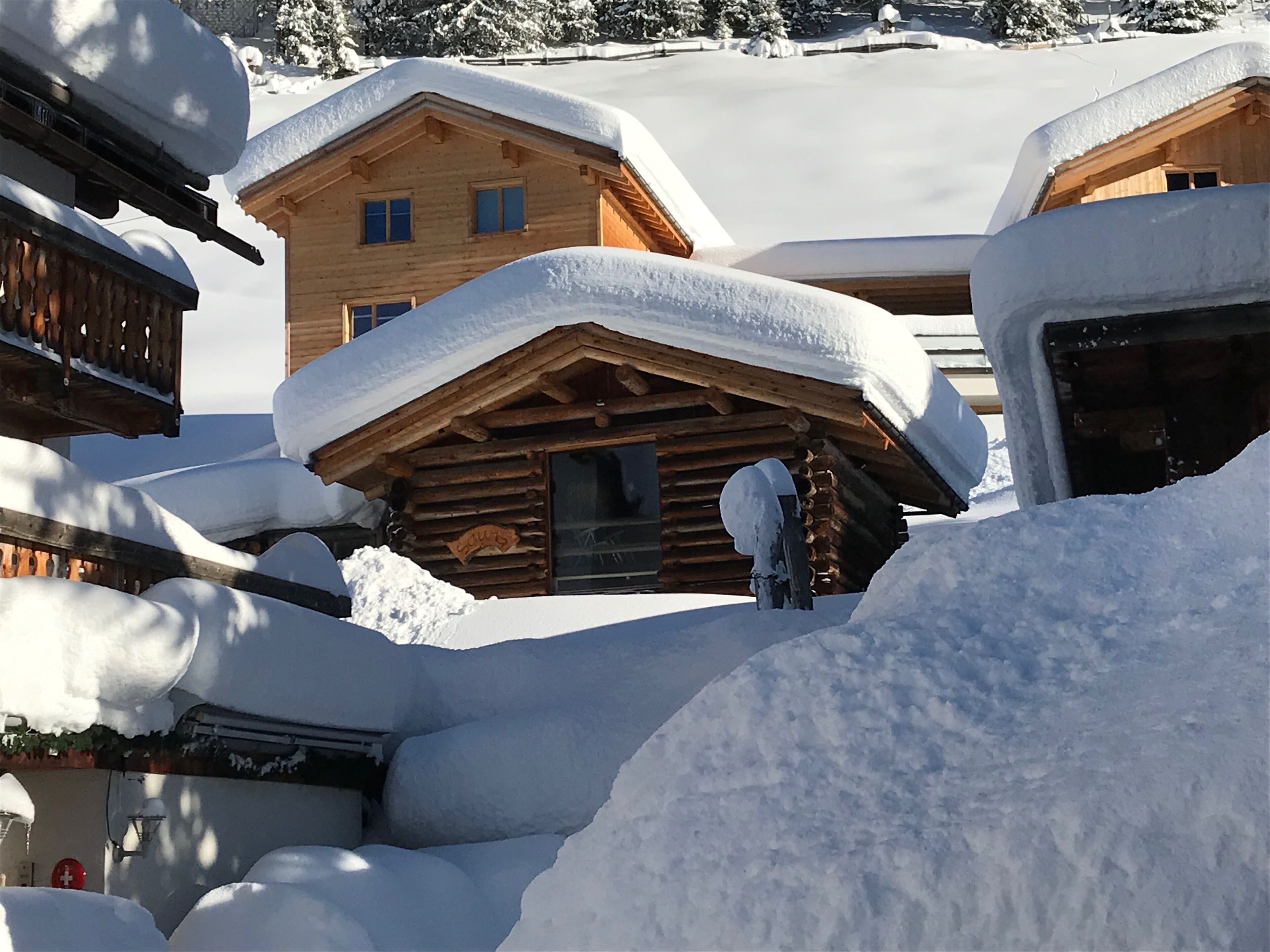Una baita di legno con tetto innevato e una finestra ben visibile.
