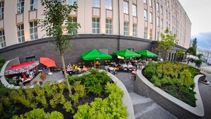 A courtyard with outdoor seating, green umbrellas, and a landscaped garden. - ALFAVITO Kyiv Hotel (Kyiv)