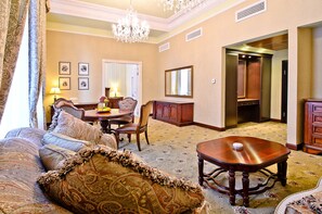 A spacious living room with a large sofa, a dining table, and a chandelier. - ALFAVITO Kyiv Hotel (Kyiv)