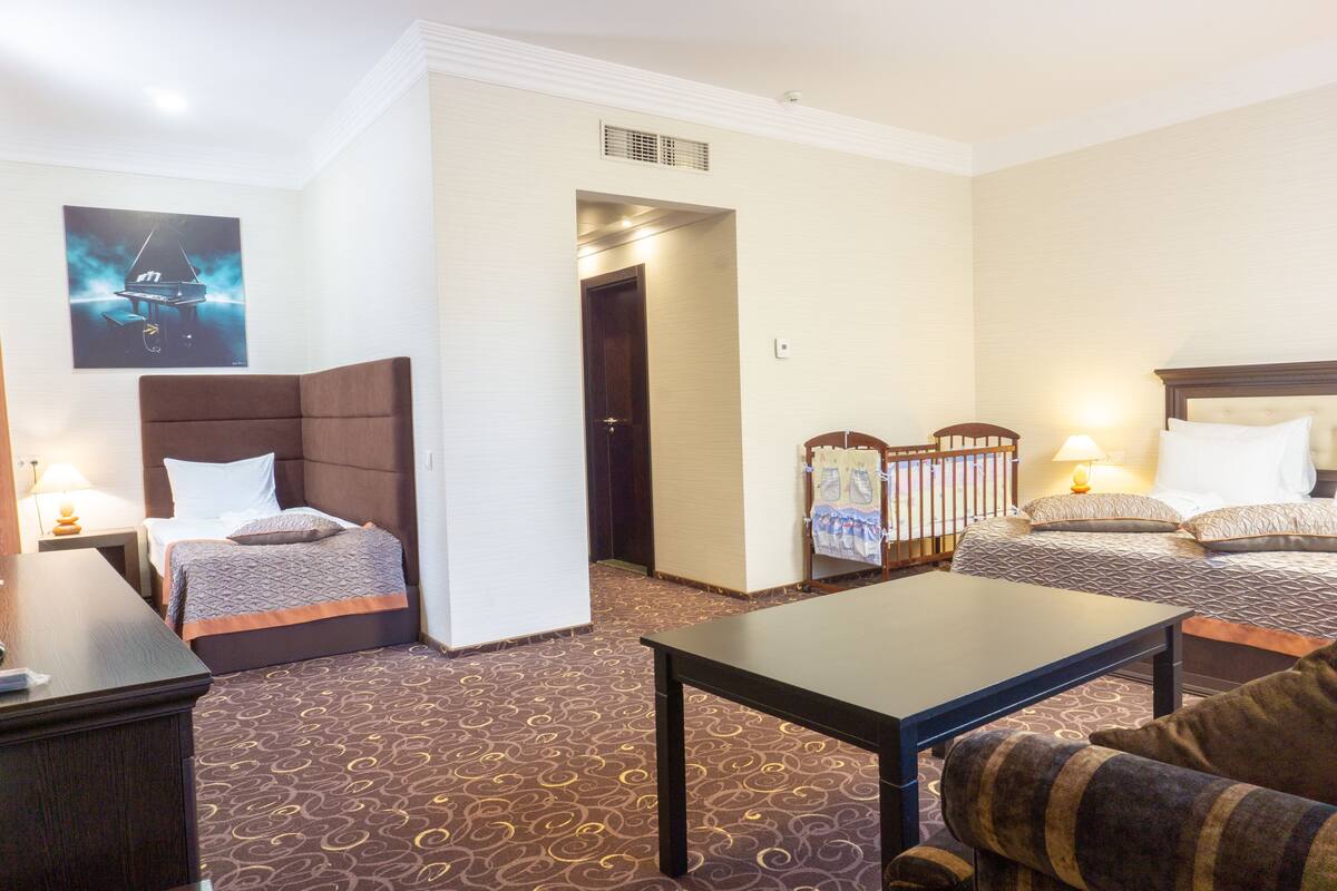 Ein Hotelzimmer mit zwei Betten, einem Schlafsofa, einem Tisch und einem Bild an der Wand.