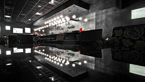 A modern bar area with a reflective floor, multiple seating options, and a bar counter with various bottles and glasses. - ALFAVITO Kyiv Hotel (Kyiv)