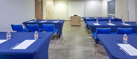 Una sala de conferencias con mesas, sillas y un atril.