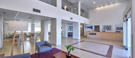 A spacious lobby with a reception desk, seating area, and a staircase connecting two floors.