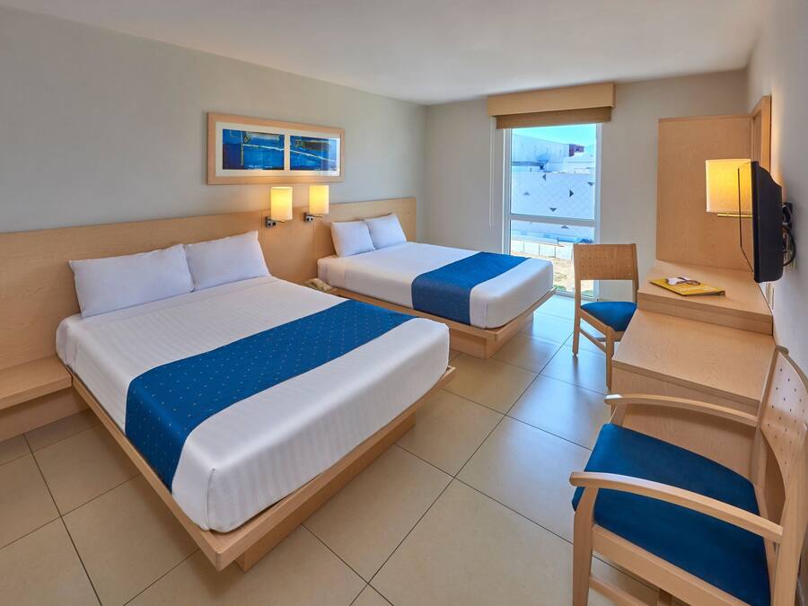 A hotel room with two beds, a desk, a chair, a TV, and a window with a view.