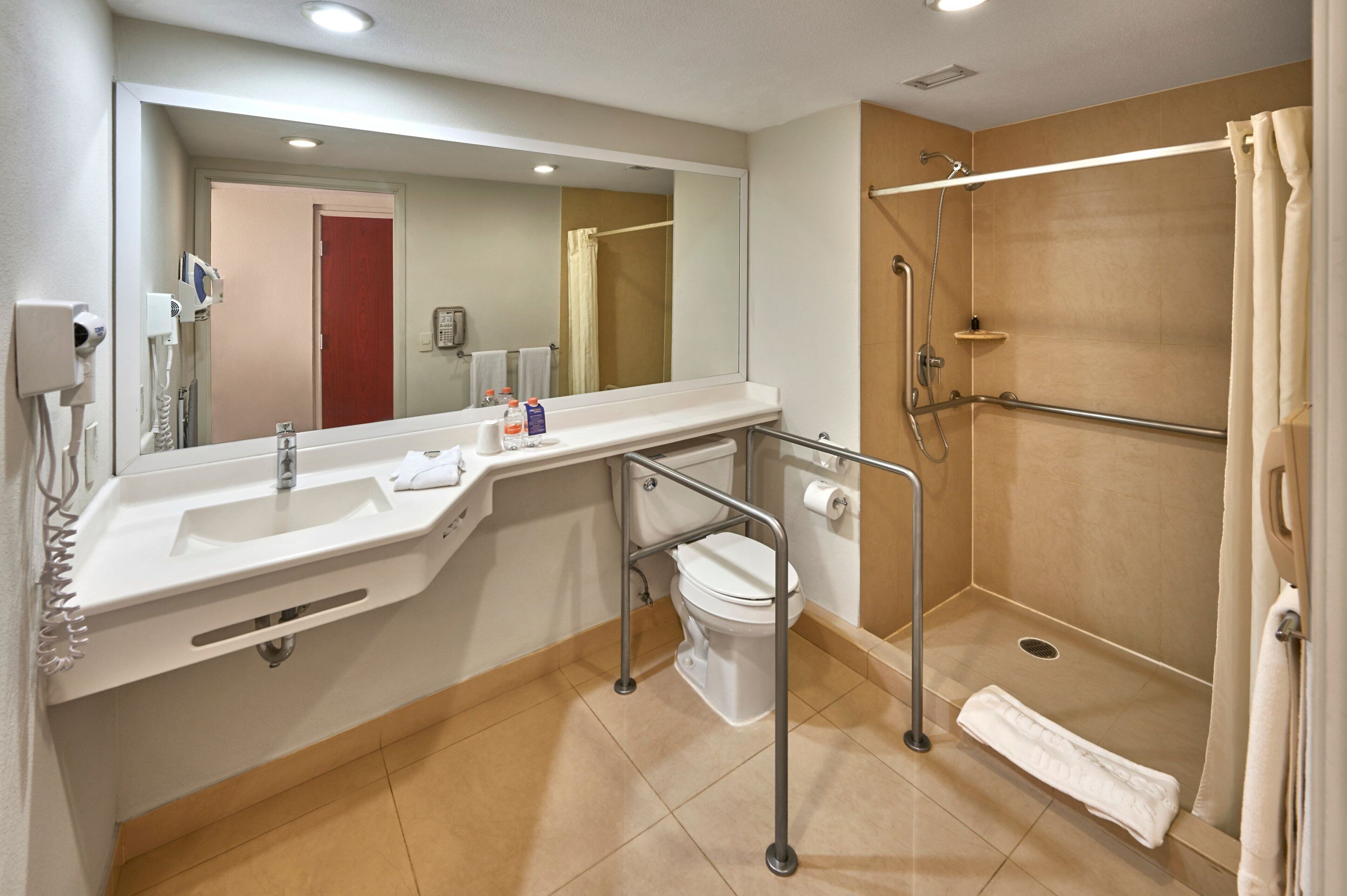 A bathroom with a sink, toilet, shower, and a mirror.