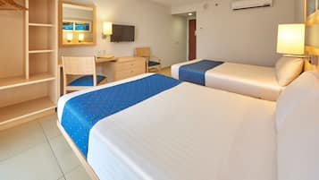 Habitación de hotel con dos camas, un escritorio, una silla, un armario, un televisor y un aire acondicionado.