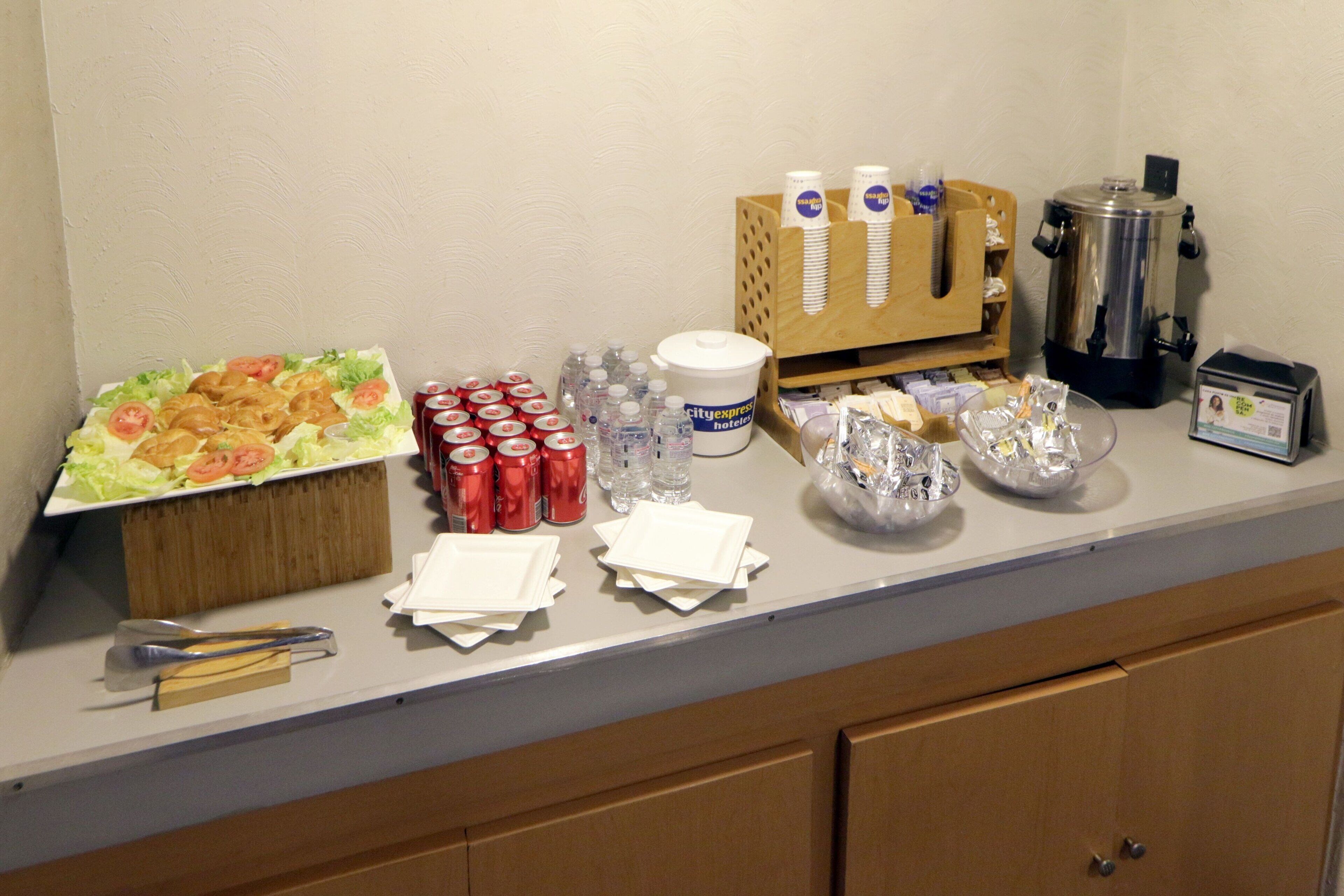 Una mesa de buffet con comida, bebidas y salsas.