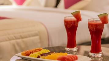 Una mesa de comedor con una bandeja de frutas y dos vasos de bebida roja, probablemente un batido o jugo, con trozos de sandía en el borde.