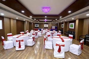 A conference room with round tables and chairs, white tablecloths, and red sashes. - Best Western Plus Ramachandra (Visakhapatnam)