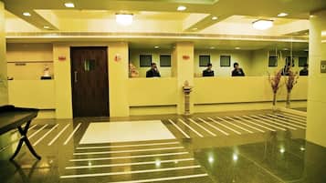 A hotel reception area with a reception desk, a waiting area with a bench, and a reception counter with a receptionist.