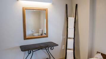 A bathroom with a mirror, a toilet, a towel rack, and a bed.