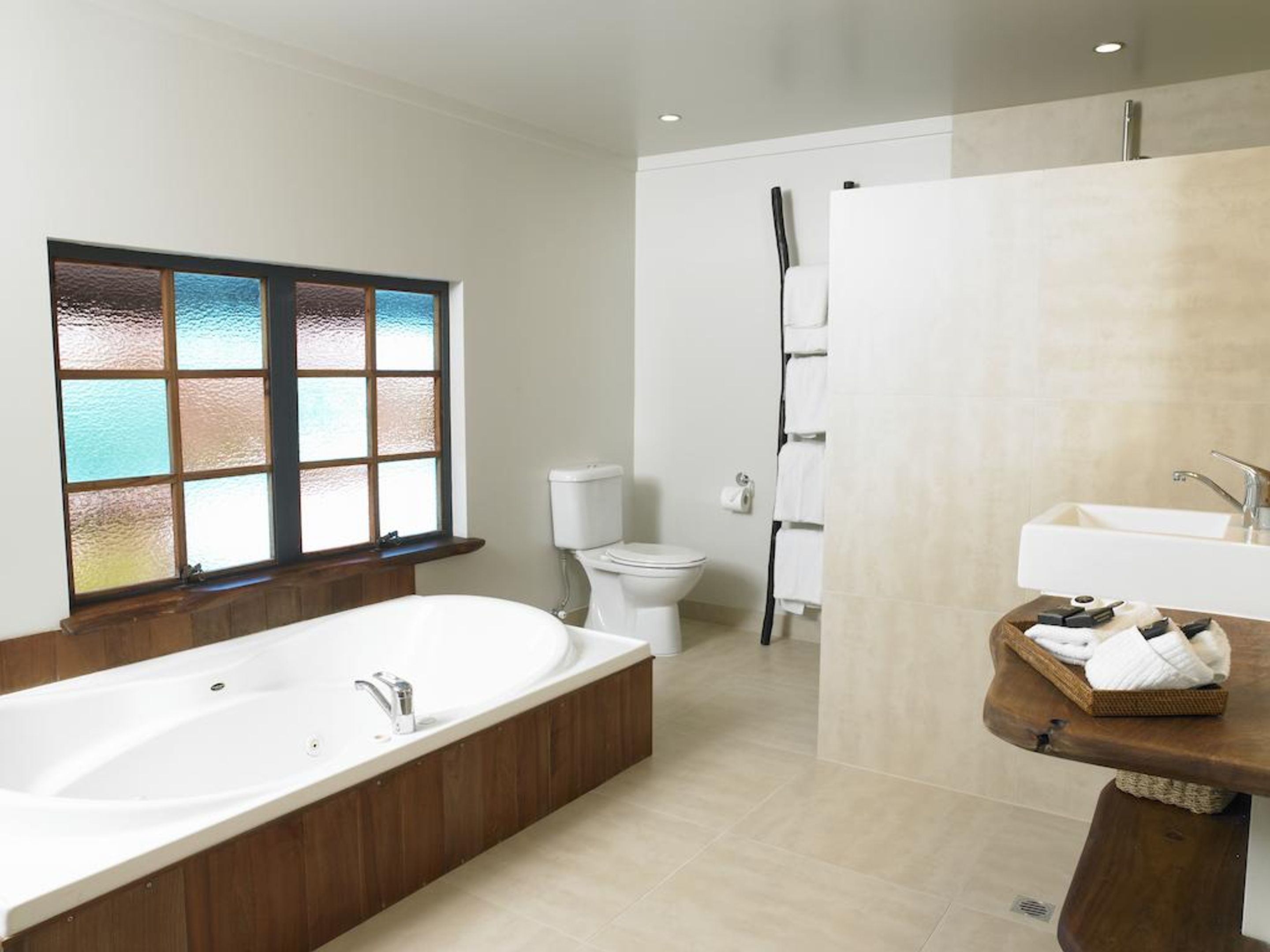 Et moderne badeværelse med et fristående badekar, toilet, bruseniche og et håndvaskarrangement med vask og håndklædestang.