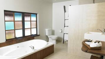 Et moderne badeværelse med et fristående badekar, toilet, bruseniche og et håndvaskarrangement med vask og håndklædestang.