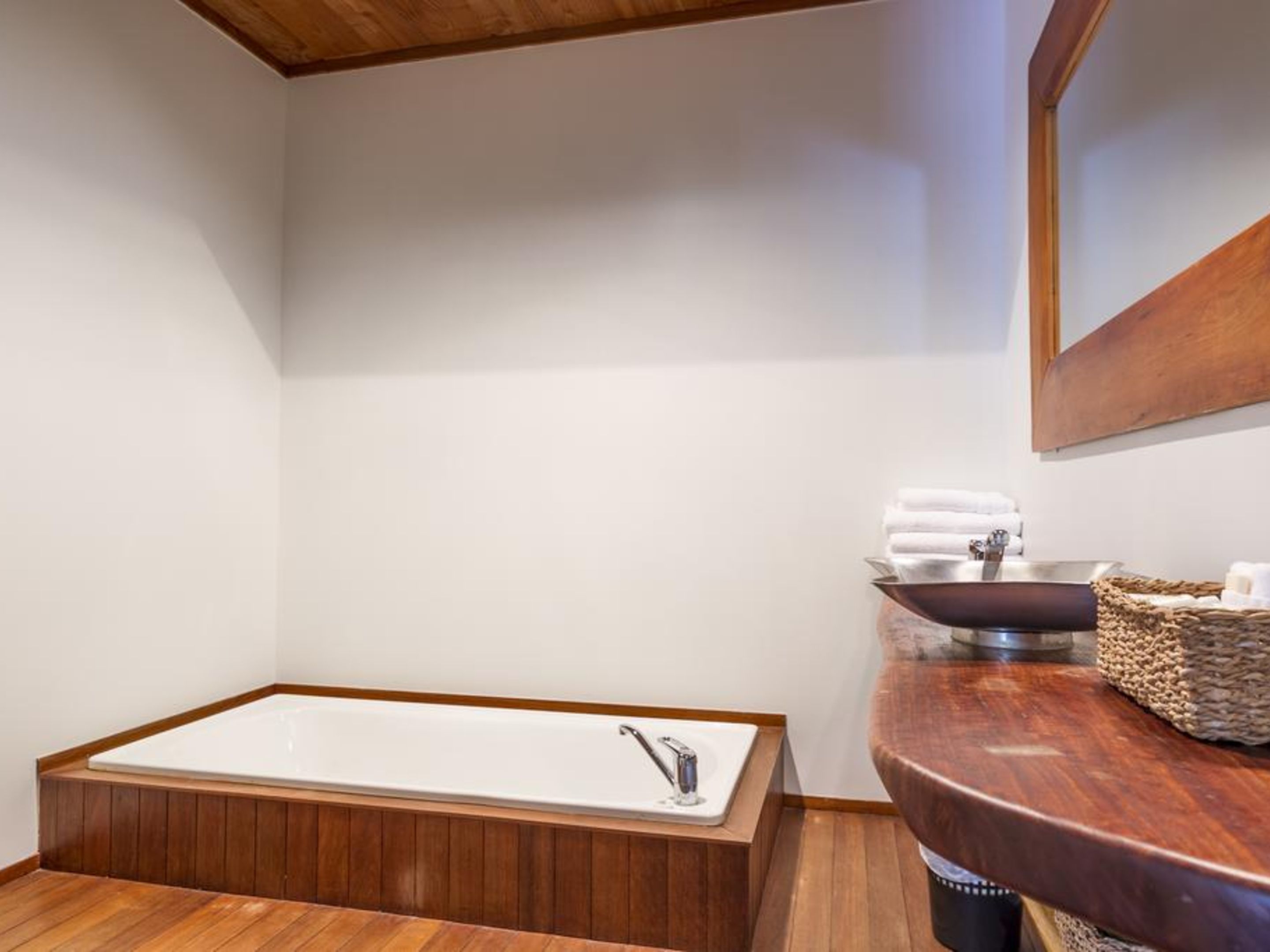 A modern bathroom with a freestanding bathtub, a wooden vanity with a sink, and a large mirror.