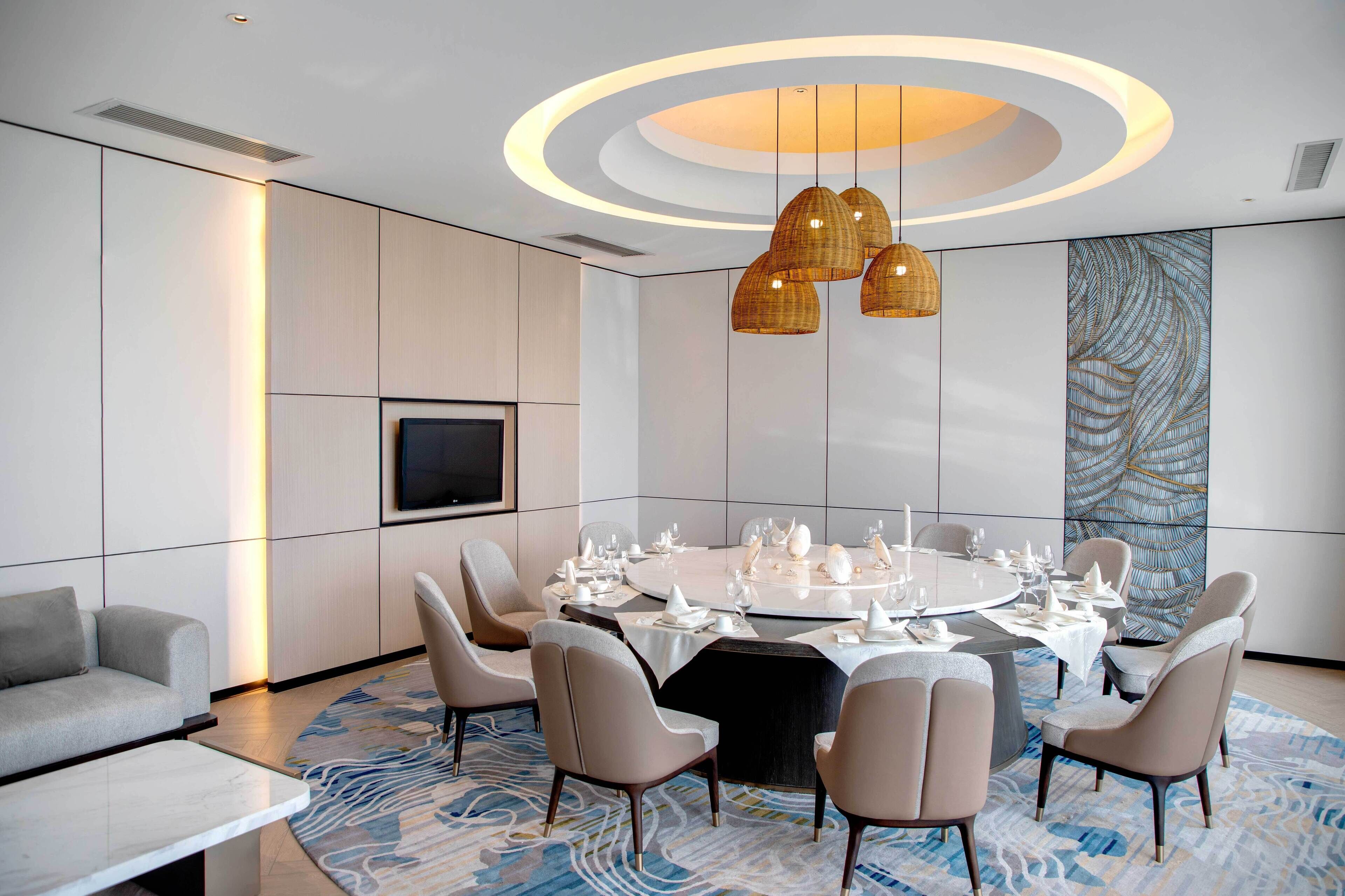 A modern dining area with a round table set for a meal, surrounded by chairs.
