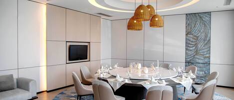A modern dining area with a round table set for a meal, surrounded by chairs.