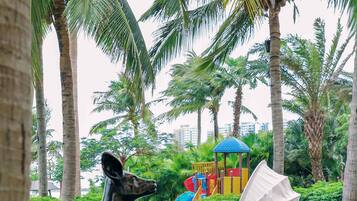 A park with palm trees, a playground, and two statues of deer.