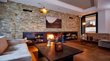 Una sala de estar moderna con pared de piedra, chimenea, sofá y mesa de centro.