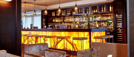 A bar area with a fireplace, seating, and a well-stocked liquor shelf.