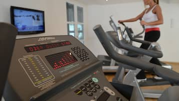 Ein Fitnessraum mit Cardiogeräten und einem digitalen Bildschirm.