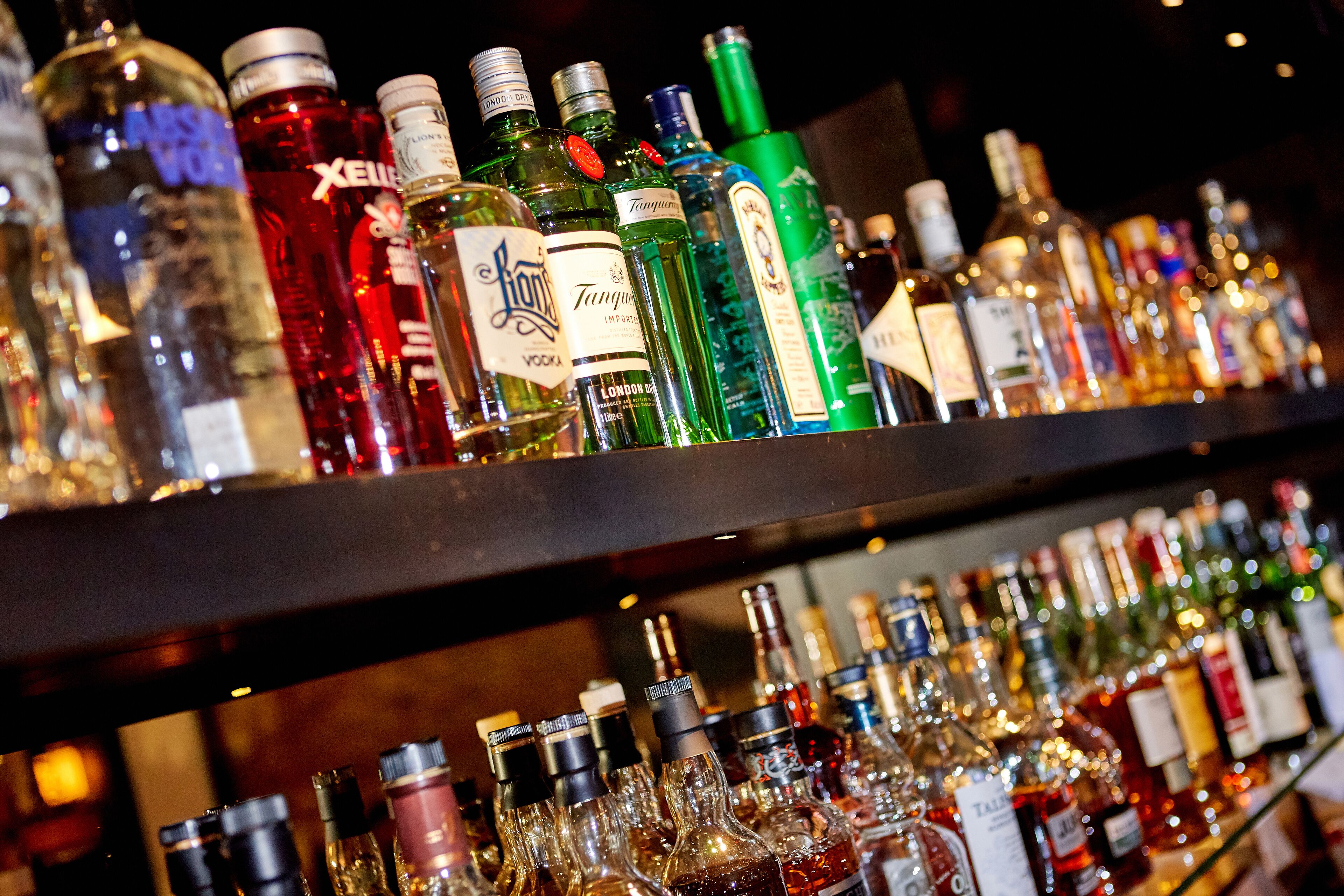 Una estantería de bar llena de diferentes botellas de licores.
