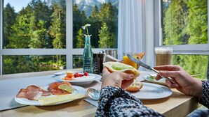 Una mesa con comida y bebidas, una ventana con vista a la montaña y una botella de agua.