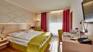 Habitación de hotel con cama, escritorio, silla y espejo.