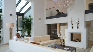 Una sala moderna con sofá, mesa de centro, chimenea y candelabro.