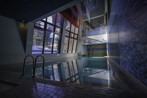 An indoor swimming pool with clear glass walls, a tiled floor, and a view of the outside. - Euphoria Club Hotel & Resort (Samokov)