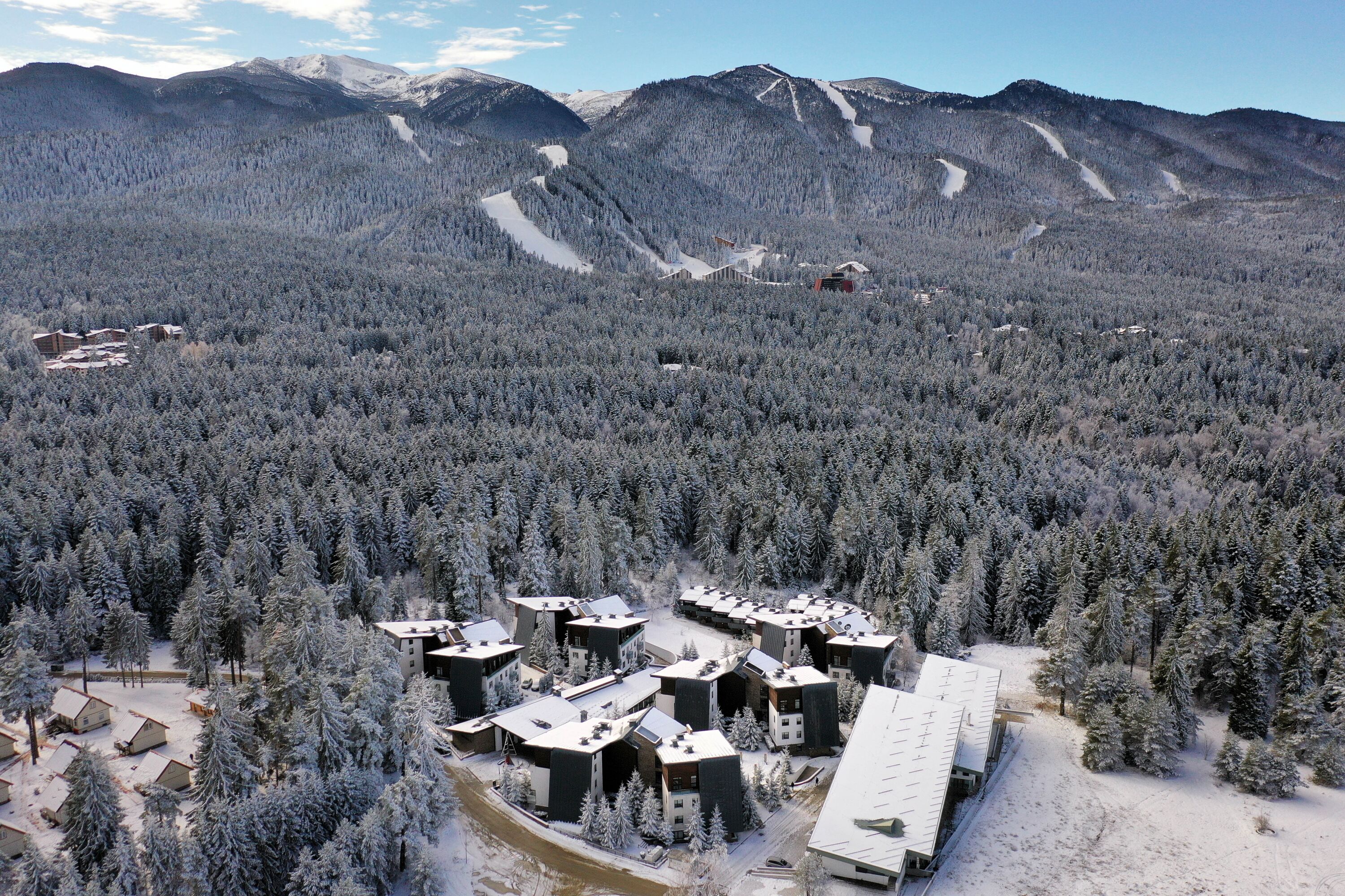 A snow-covered lodge with multiple cabins and a ski slope in the background.