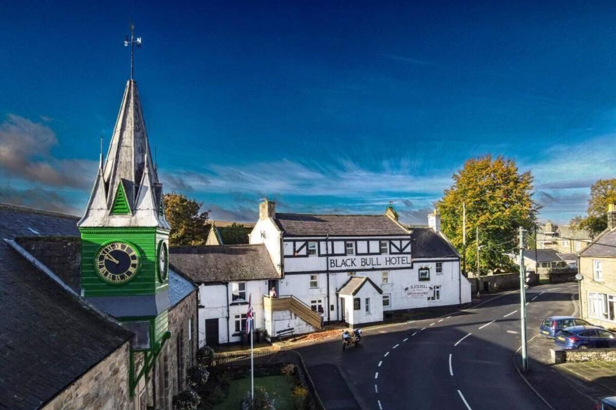 Un edificio tradizionale con una torre dell'orologio e un cartello che indica l'Hotel Black Bull.