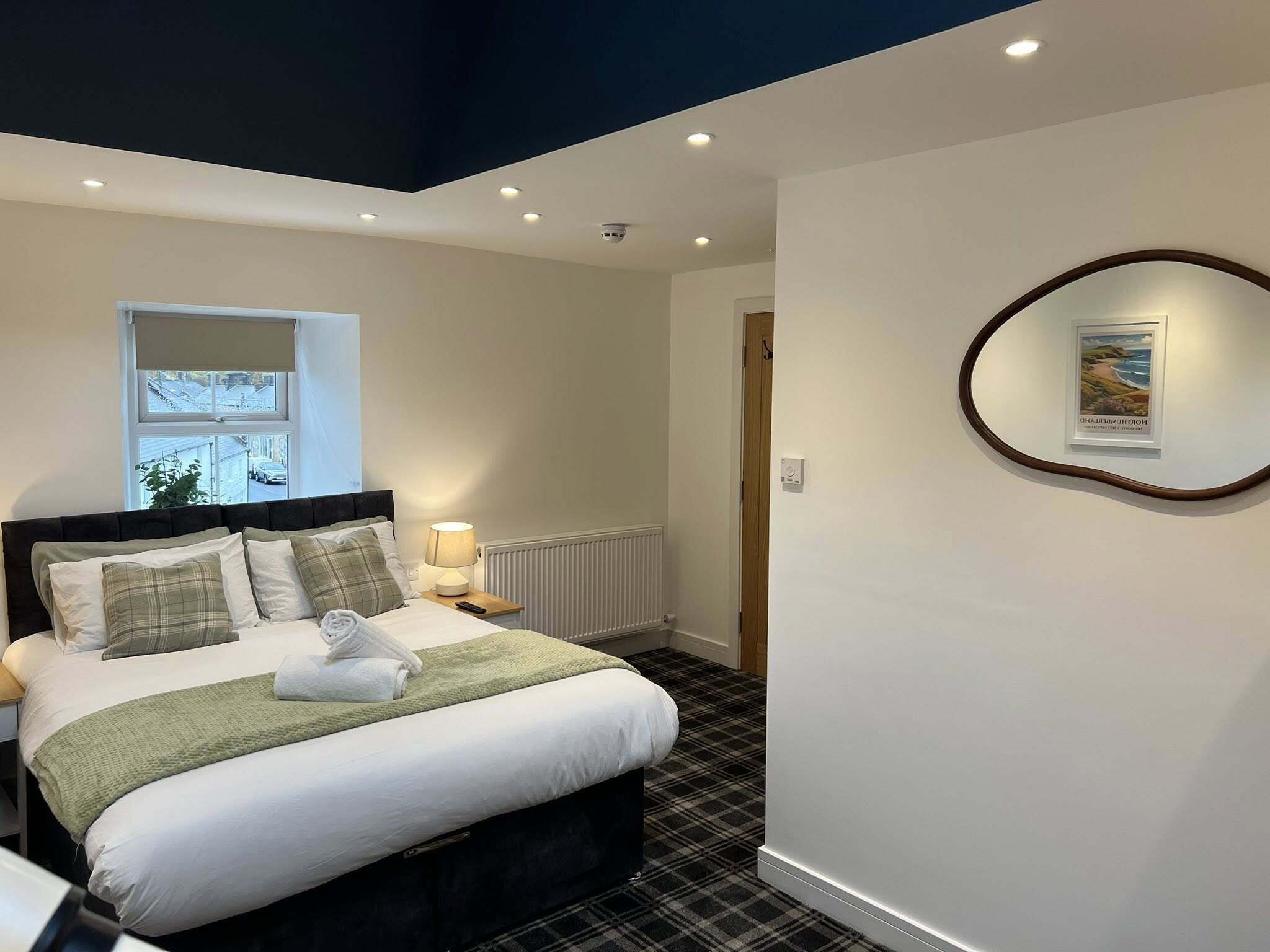 A bedroom with a bed, a window, a radiator, and a framed picture on the wall.