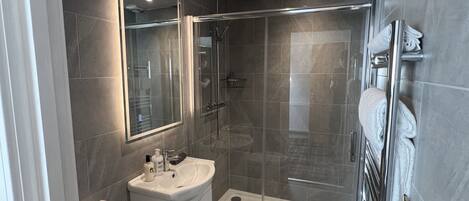 Un baño moderno con cabina de ducha de vidrio, inodoro y lavabo con espejo.