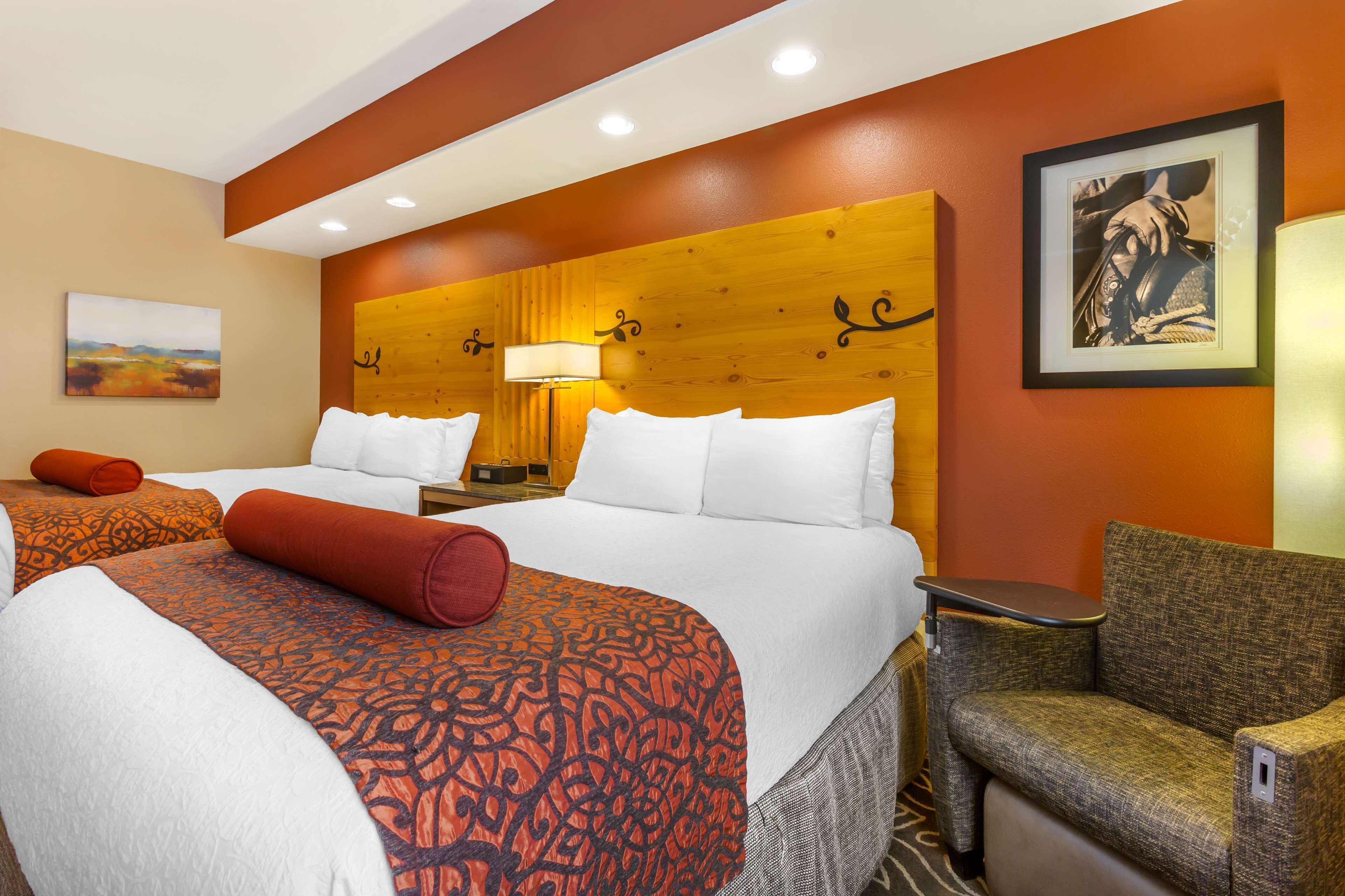 A hotel room with two beds, a sofa, a lamp, and a framed picture on the wall.