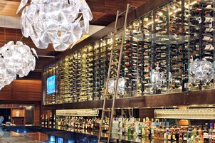 Una zona de bar con una amplia estantería para vinos, un televisor y una barra.