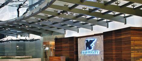 A JW Marriott hotel entrance with a modern design, including a wooden facade and a glass wall.