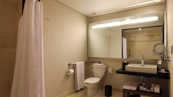 A bathroom with a toilet, sink, and mirror.