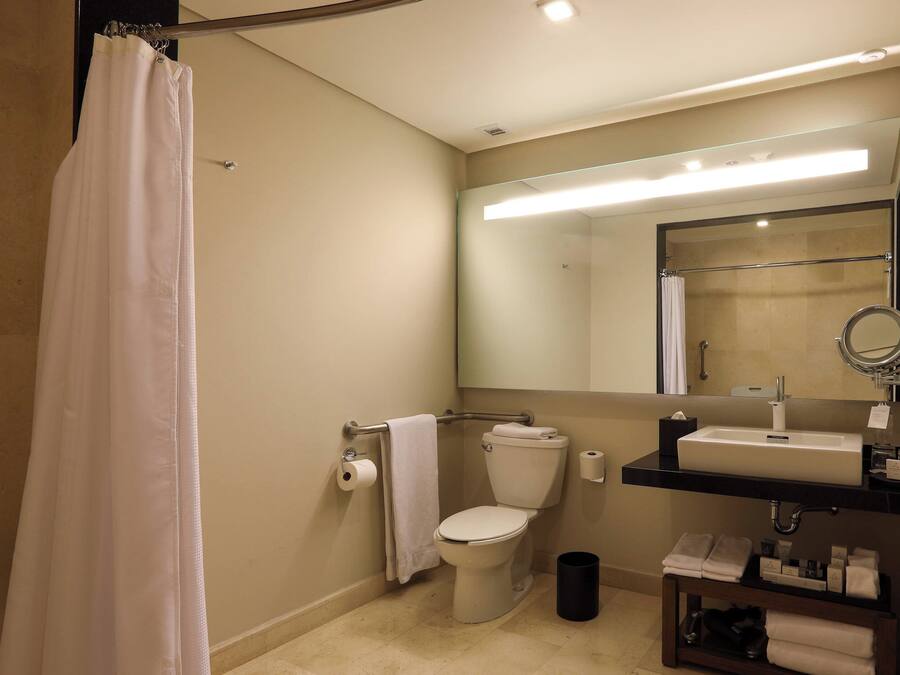 A bathroom with a toilet, sink, and mirror.