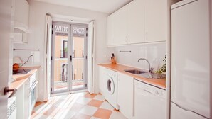 Cocina moderna con armarios blancos, lavadora y pileta.