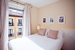 A hotel room with a bed, curtains, a window, and three framed pictures on the wall. - Apartment in the Centre (Madrid)