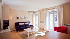 Una sala moderna con un sofá, una mesa de centro, un televisor y un comedor con sillas.