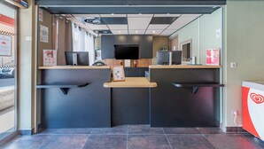 A reception area with a modern design, featuring a reception desk, a flat-screen TV, and a potted plant. - Appart'City Confort Marseille Centre Prado Velodrome (Marseille)