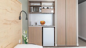 A compact kitchenette with a microwave, a small refrigerator, and a fruit bowl on the counter. - Appart'City Confort Marseille Centre Prado Velodrome (Marseille)