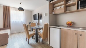 A compact living space with a dining area, kitchenette, and a TV mounted on the wall. - Appart'City Confort Marseille Centre Prado Velodrome (Marseille)
