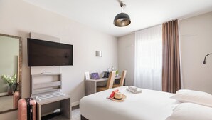 A hotel room with a bed, a desk, a television, a suitcase, and a mirror. - Appart'City Confort Marseille Centre Prado Velodrome (Marseille)