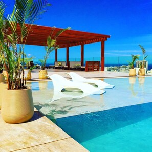 Una piscina al aire libre, sillones reclinables de piscina