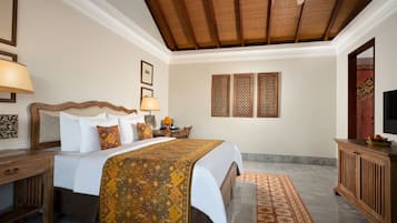 Habitación de hotel con cama, mesita de noche, escritorio, silla, televisor y ventilador de techo.